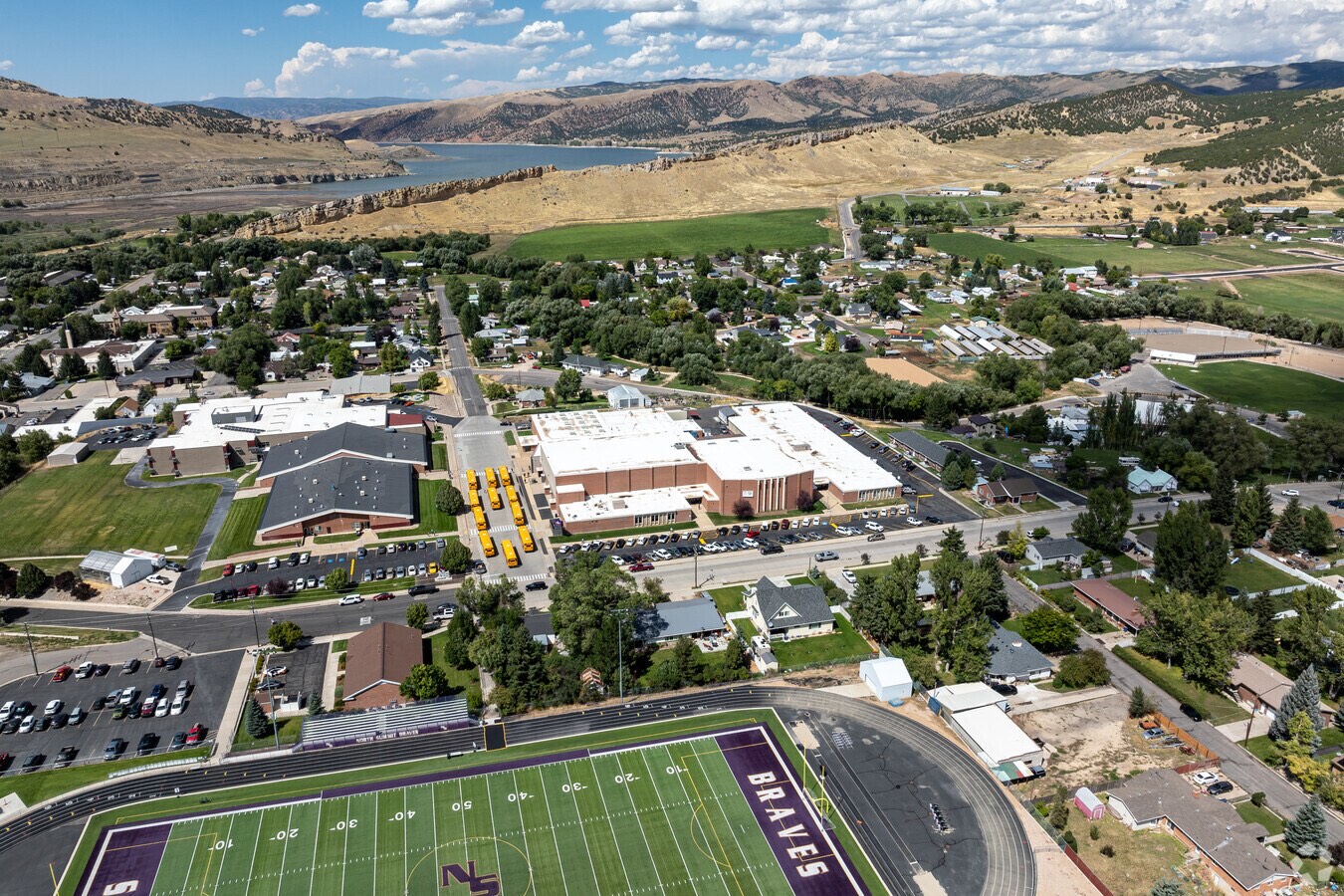 Aerial view of North Summit High School and the Braves football field in Coalville, Utah, with Echo Reservoir and the surrounding hills beyond.